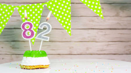 Beautiful festive background with the number 82  with a cake and lit candles, space saving for any holiday. Garland with birthday decorations for a postcard.Decorations are multi-cの写真素材