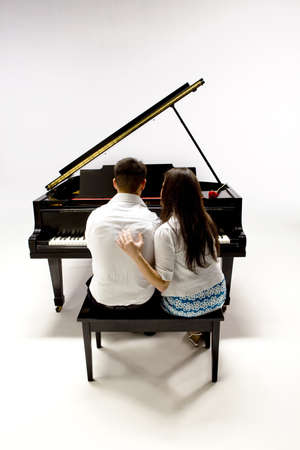 Couple with Grand piano 1 in white shirt, black pants and sundress sitting at piano bench with red rose.の写真素材