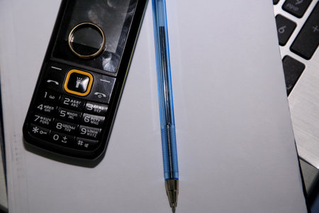 Pencil and mobile phone on the keyboard of a laptop computer.の写真素材