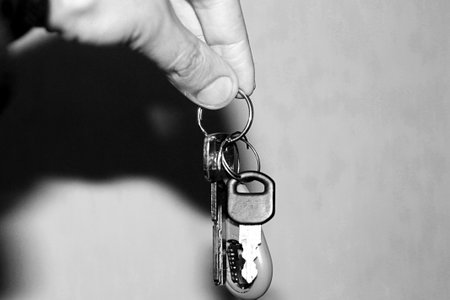 Hand holding a key with a key ring. Black and white image.の写真素材