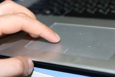 Close-up of a man's hand pressing a button on a laptop keyboard