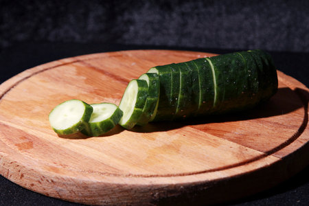 Sliced cucumber on a wooden board on a black backgroundの写真素材