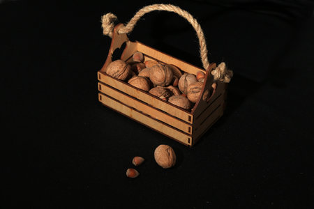 Walnuts in a wooden box on a black background with a rope