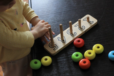 little girl playing with wooden abacus on black wooden table background.