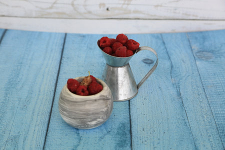 Raspberries in a ceramic vase on a blue wooden background