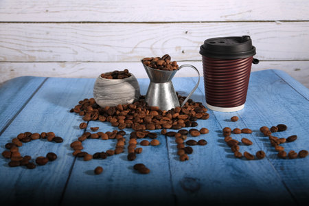 Coffee beans and cup of coffee on a blue wooden background