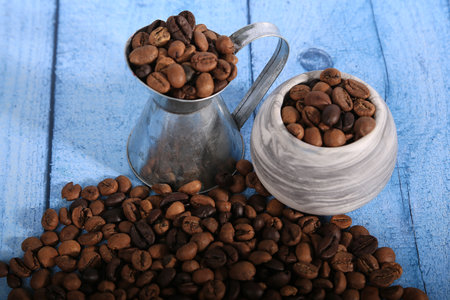 Coffee beans in a cup on a blue wooden background.