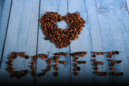 Coffee beans in the shape of a heart on a blue wooden backgroundの写真素材