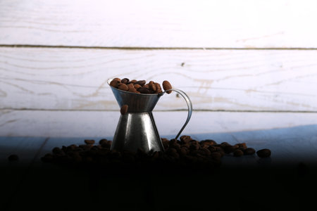 Coffee beans in a metal vase on a wooden backgroundの写真素材