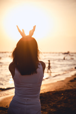 Silhouette of a young woman enjoying the sunset on the beachの写真素材