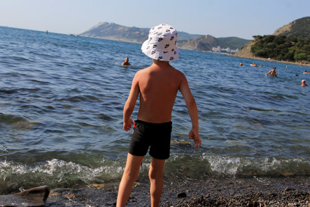 boy on the seashore in a white hat and black shortsの写真素材