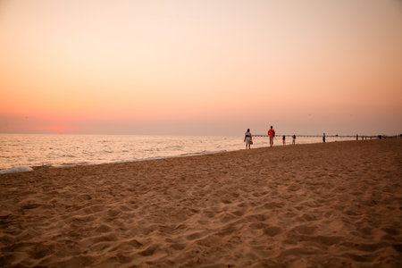 Sunset on the beach of the sea. People walk along the sandy beach.の写真素材