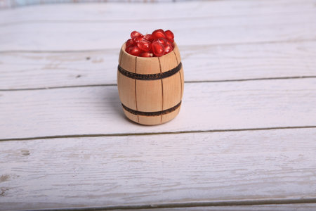 Pomegranate seeds in a wooden barrel on a white wooden backgroundの写真素材