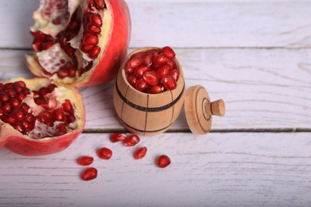 Ripe pomegranate fruit and wooden barrel on white wooden backgroundの写真素材