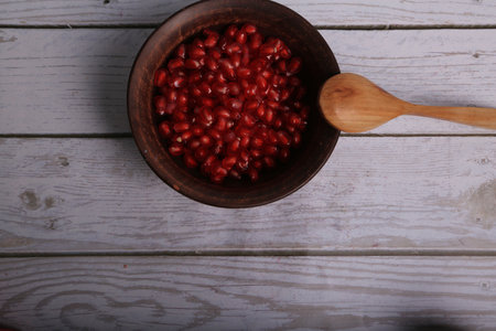 Pomegranate seeds in a wooden bowl on a wooden backgroundの写真素材