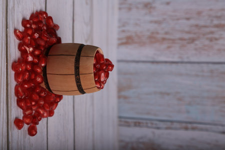 Pomegranate seeds in a wooden barrel on a wooden backgroundの写真素材