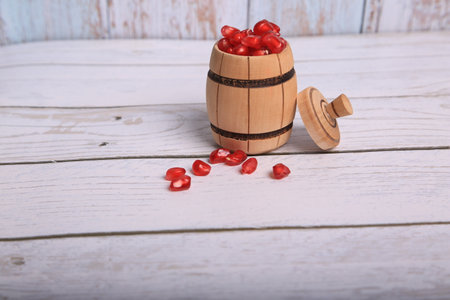Pomegranate seeds in a wooden barrel on a white wooden backgroundの写真素材