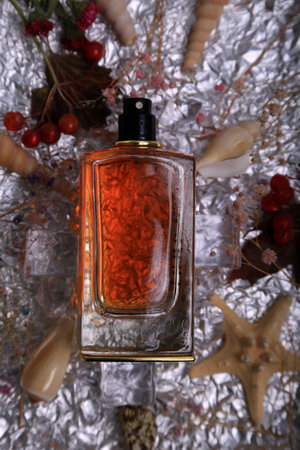 Bottle of perfume and Christmas decorations on a silver background. Top view.