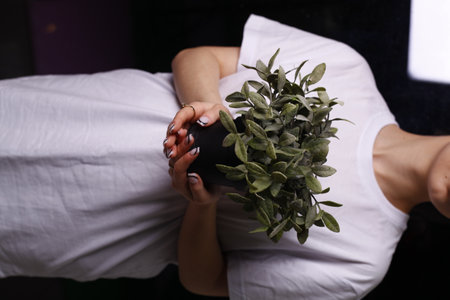 Woman in a beauty salon with a bouquet of green leaves.の写真素材