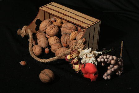 Walnuts and nuts in a wooden box on a black background.