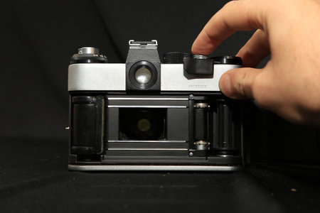 Old camera in the hands of a man on a black background.