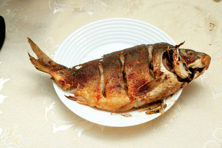 Fried fish on a white plate on a table in a restaurantの写真素材