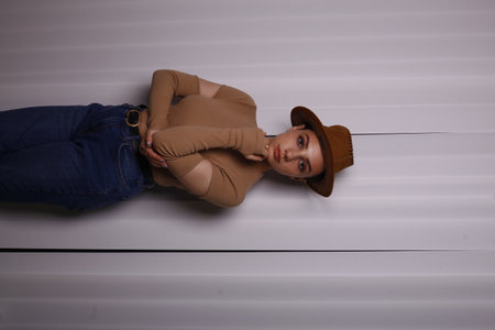 Portrait of a beautiful young woman in a hat lying on the floorの写真素材