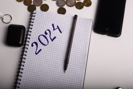 2024 new year goals with notebook, pen and coins on white backgroundの写真素材