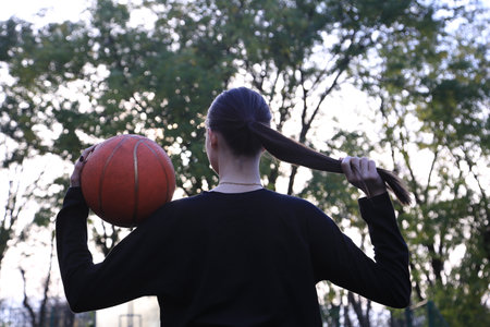 Young woman playing basketball in the park, back view. Sport conceptの写真素材