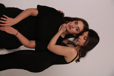 Portrait of two beautiful women in black clothes lying on the floorの写真素材