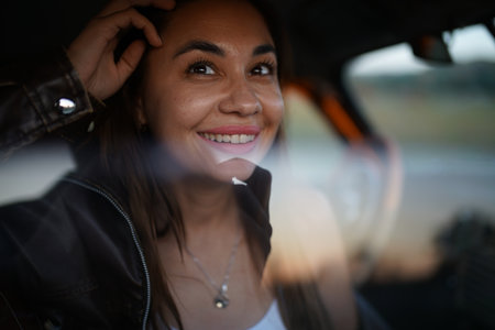 Portrait of a beautiful young woman smiling and looking at camera while sitting in a carの写真素材