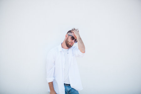 Portrait of a handsome young man in a white shirt and sunglasses on a white backgroundの写真素材