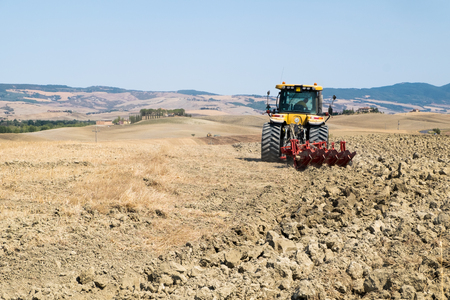 Peasant on the tractor while preparing the field for sowingの写真素材