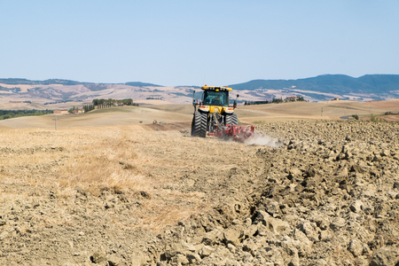 Peasant on the tractor while preparing the field for sowingの写真素材