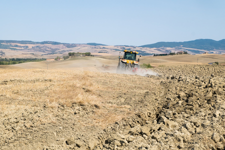 Peasant on the tractor while preparing the field for sowingの写真素材
