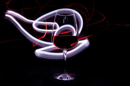 Red and white lights with red wine glass on black backgroundの写真素材