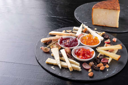 Cheese board with nuts and marmalades on a black slate background - gastronomy - gourmetの写真素材