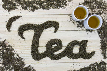 tea text make by tea leaf on wooden background with tea small cupの写真素材