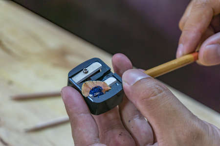Man sharpening the pencil with pencil sharpenerの写真素材