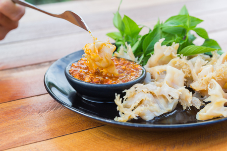 use fork stabbing boiled jellyfish with peanut dipping sauce on the black plateの写真素材
