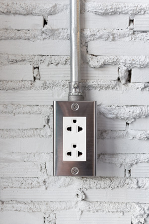 Electric plug outlet on grunge cement brick wall background.の写真素材