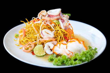 Crispy noodles with seafood spicy salad on black backgroundの写真素材