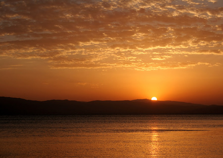 Beautiful sunset reflection in the Lake of Sevan and Geghama mountain rangeの写真素材