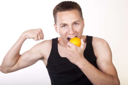 Portrait of a young attractive male eating orange.の写真素材