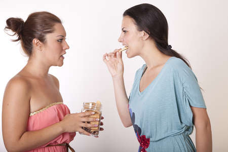 Portrait of a two young cheerful girls eating cookies.