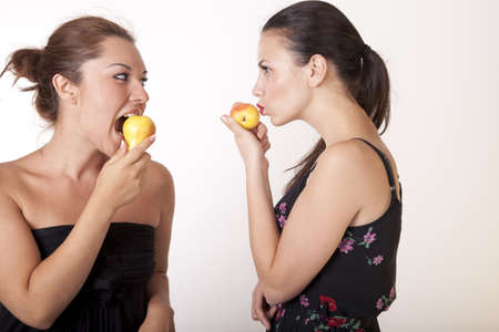 Portrait of a two young cheerful women eating pearsの写真素材
