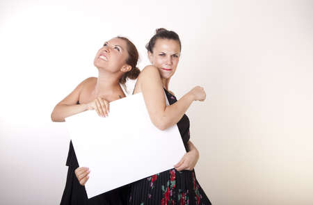 Portrait of a two beautiful sexy women holding a white board.の写真素材