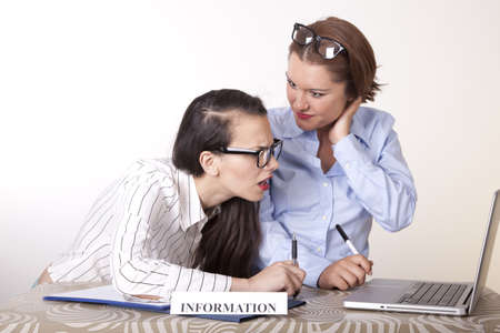 Portrait of a two young beautiful female receptionists working at the information desk.の写真素材