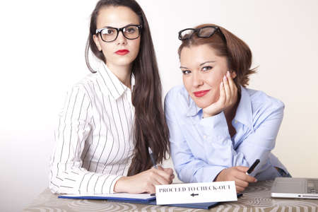Portrait of a two young beautiful female receptionists with a sign.
