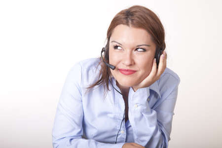 Portrait of a young beautiful secretary with headphones thinking.